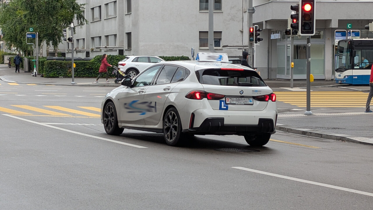 Ein Fahrschulauto steht an einer roten Ampel