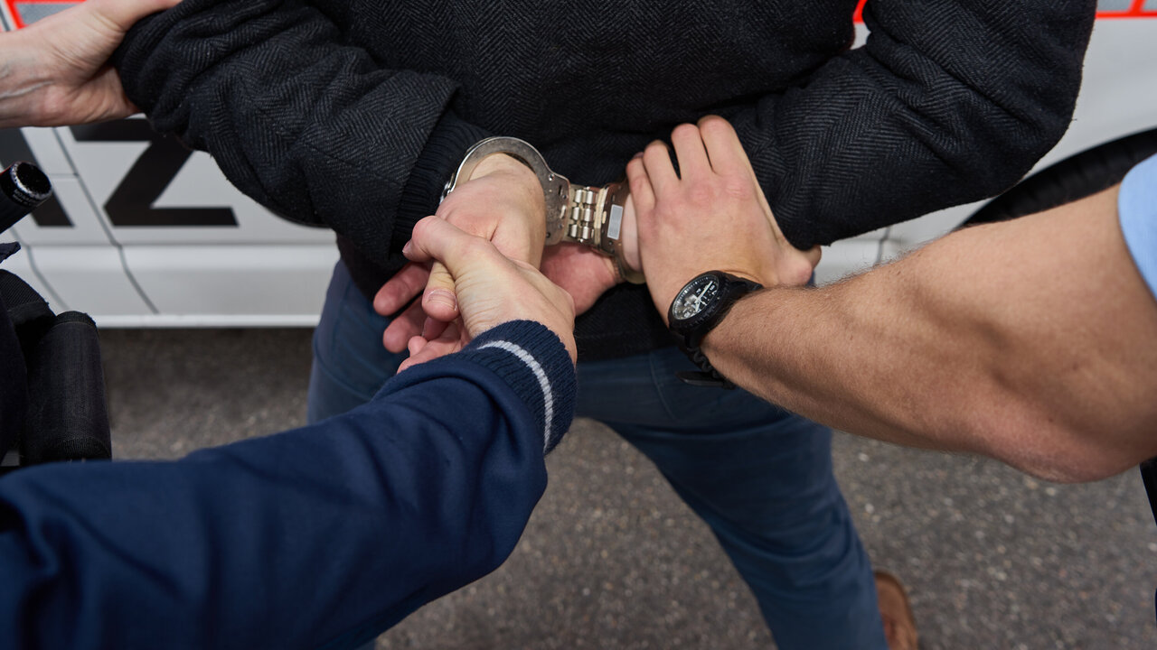 Einer Person werden Handschellen angelegt