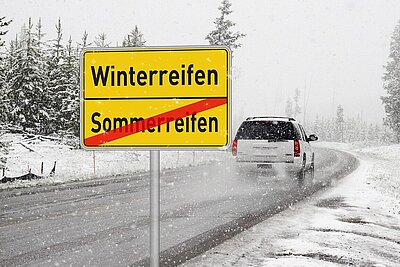 Auto auf der Strasse mit verschneitem Strassenrand.