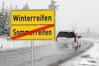 Auto auf der Strasse mit verschneitem Strassenrand.
