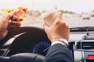 Die Pizza am Steuer zu essen, ist keine gute Idee. Wer erwischt wird, muss mit einer Verzeigung rechnen. Bild: freepik. 