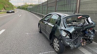 Nach der Kollision steht der stark beschädigte Peugeot in falscher Richtung auf der Autobahn. Im Hintergrund ist das unfallverursachende Fahrzeug, der Mercedes AMG zusehen. Bild: Kantonspolizei Zürich