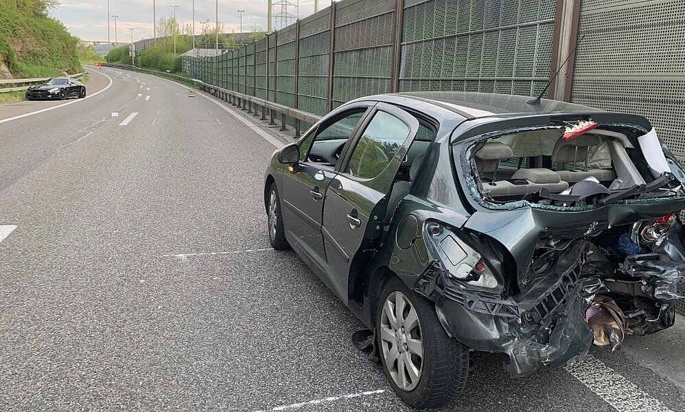 Nach der Kollision steht der stark beschädigte Peugeot in falscher Richtung auf der Autobahn. Im Hintergrund ist das unfallverursachende Fahrzeug, der Mercedes AMG zusehen. Bild: Kantonspolizei Zürich