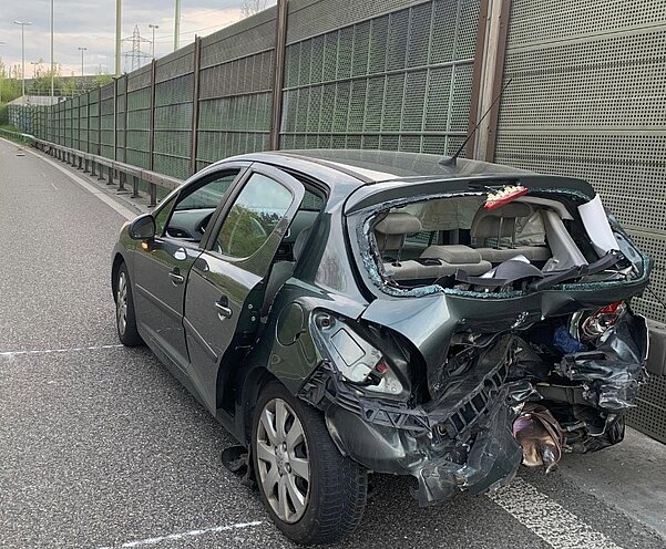Nach der Kollision steht der stark beschädigte Peugeot in falscher Richtung auf der Autobahn. Im Hintergrund ist das unfallverursachende Fahrzeug, der Mercedes AMG zusehen. Bild: Kantonspolizei Zürich