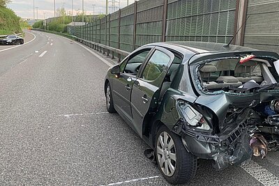 Nach der Kollision steht der stark beschädigte Peugeot in falscher Richtung auf der Autobahn. Im Hintergrund ist das unfallverursachende Fahrzeug, der Mercedes AMG zusehen. Bild: Kantonspolizei Zürich
