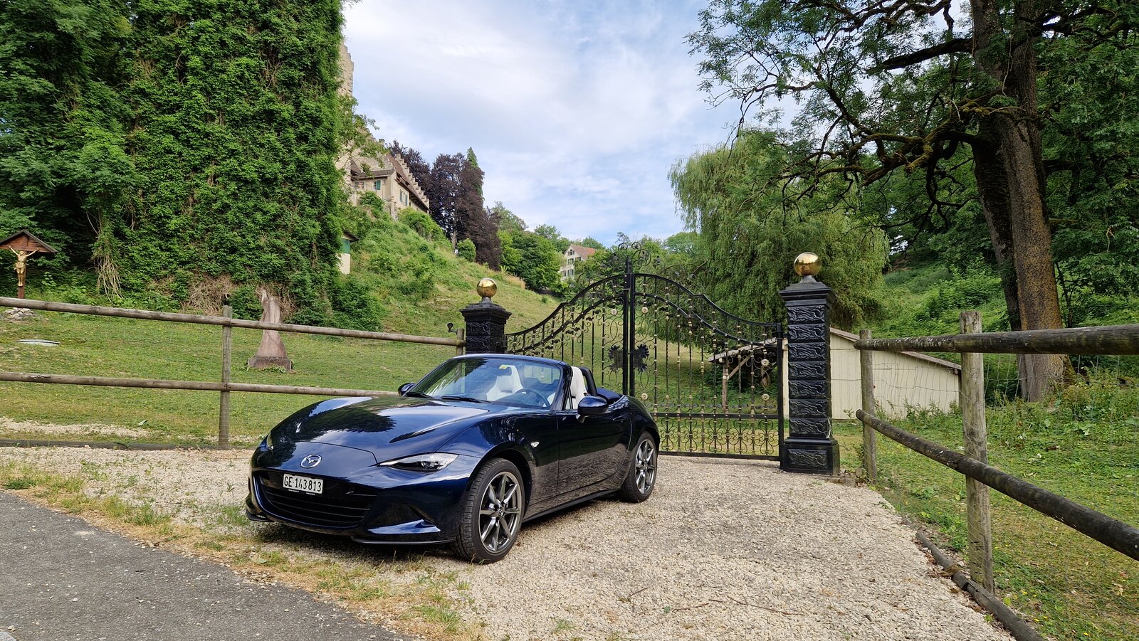 Der offene Mazda MX-5 in der Frontansicht vor dem Tor eines Landgutes.
