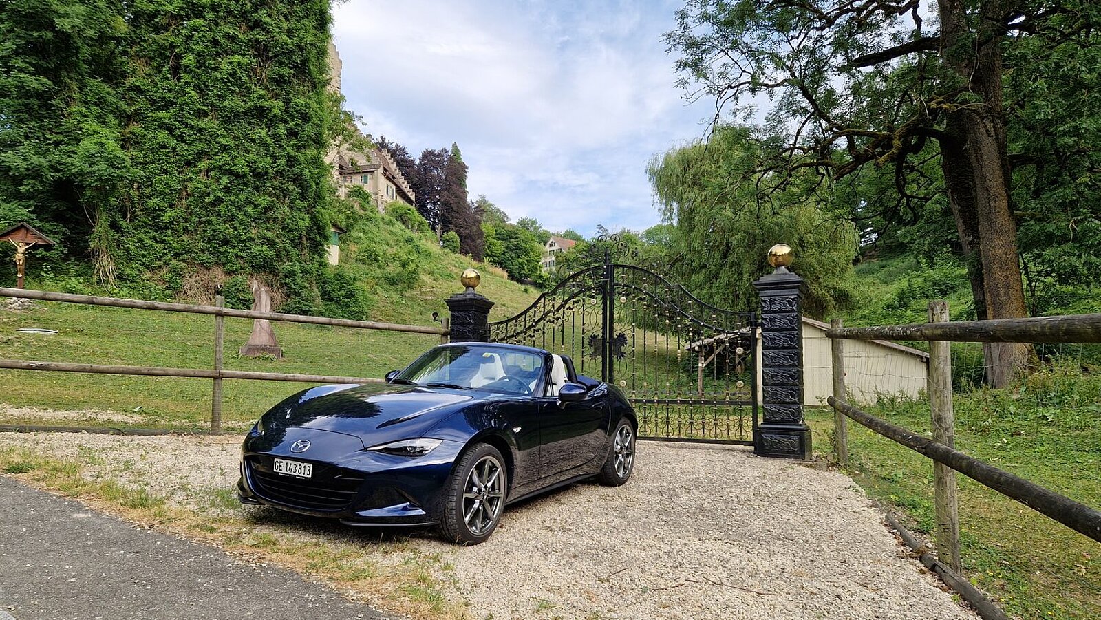 Der offene Mazda MX-5 in der Frontansicht vor dem Tor eines Landgutes.