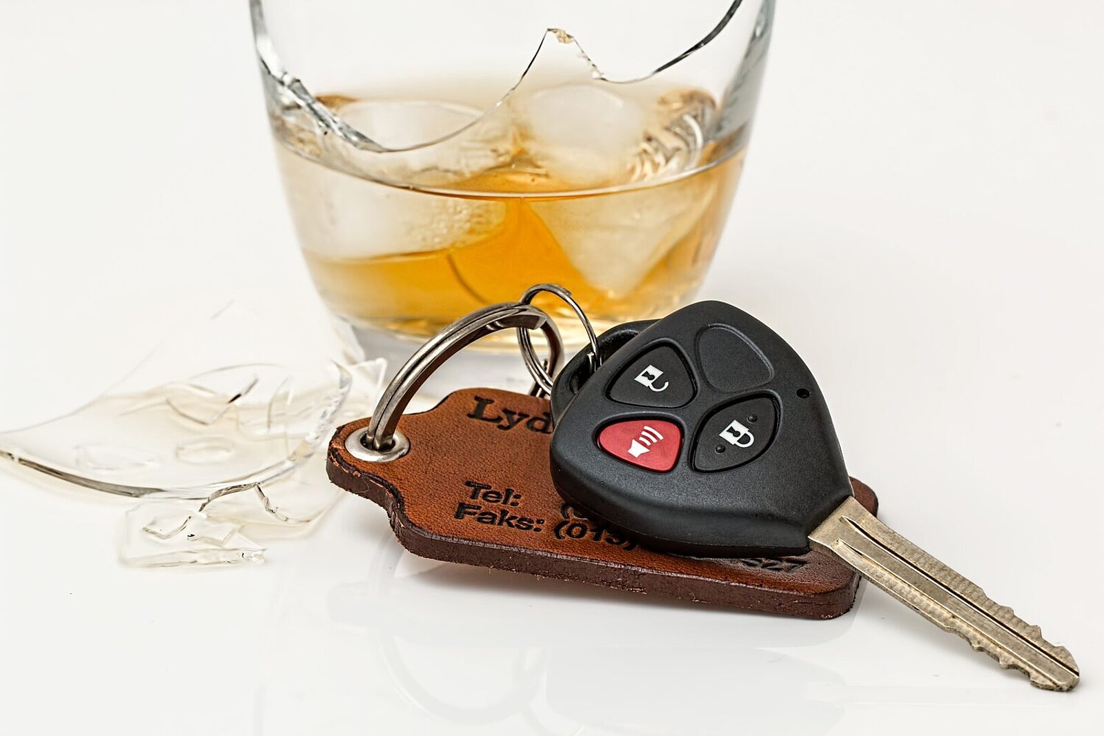 Autoschlüssel neben einem zerbrochenen Whiskey-Glas
