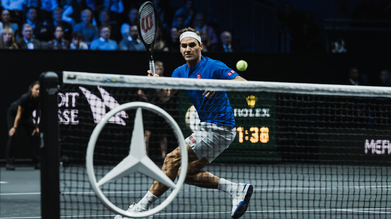 Roger Federer auf dem Tennisplatz im Vordergrund der Mercedes-Stern im Tennisnetz montiert