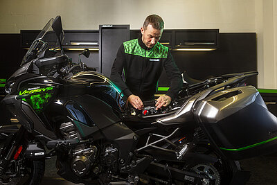 Mann entfernt Batterie an einem Motorrad.