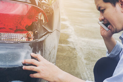 Ein Mann begutachtet einen Unfallschaden