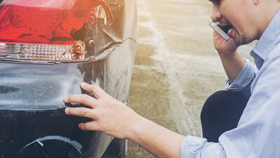 Ein Mann begutachtet einen Unfallschaden