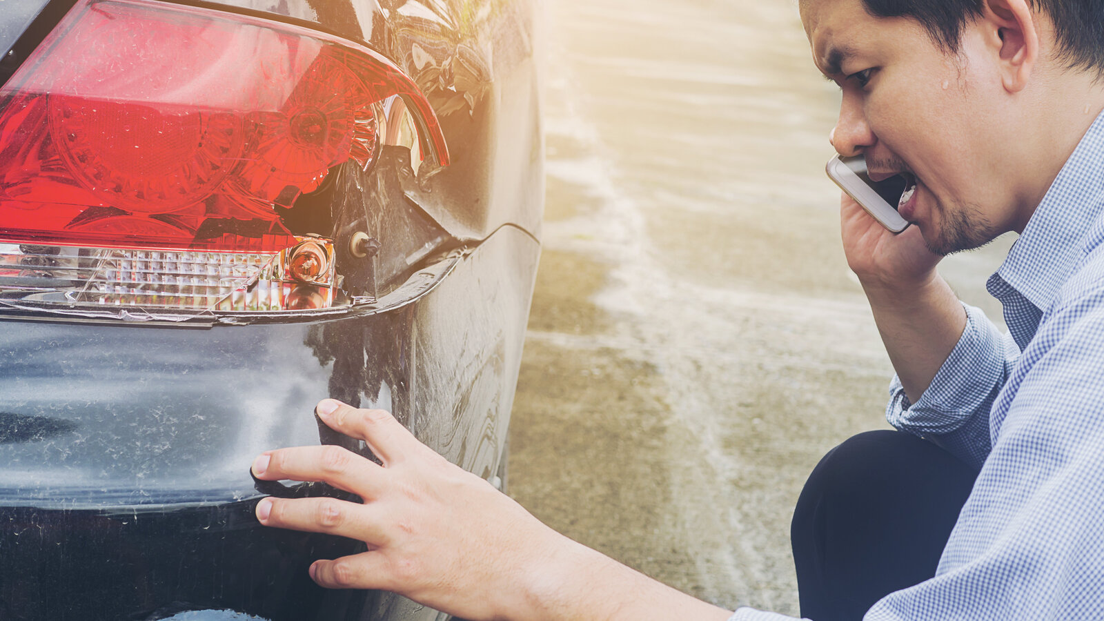 Ein Mann begutachtet einen Unfallschaden