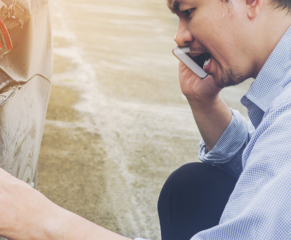 Ein Mann begutachtet einen Unfallschaden
