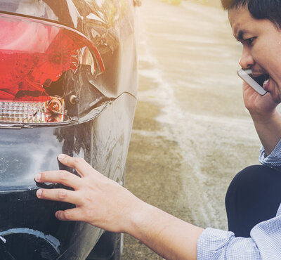 Ein Mann begutachtet einen Unfallschaden