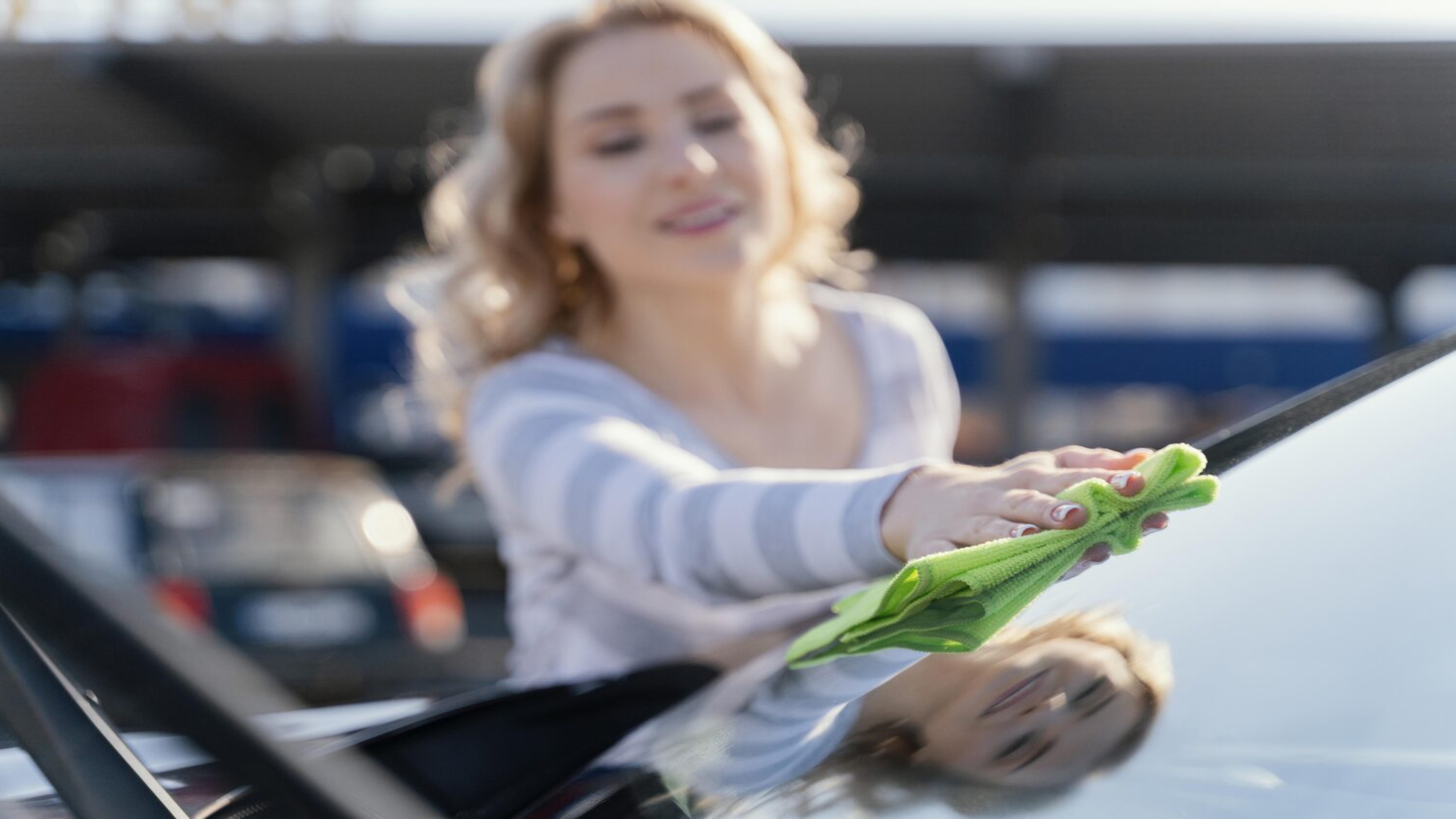 Eine Frau reinigt die Scheibe ihres Auto