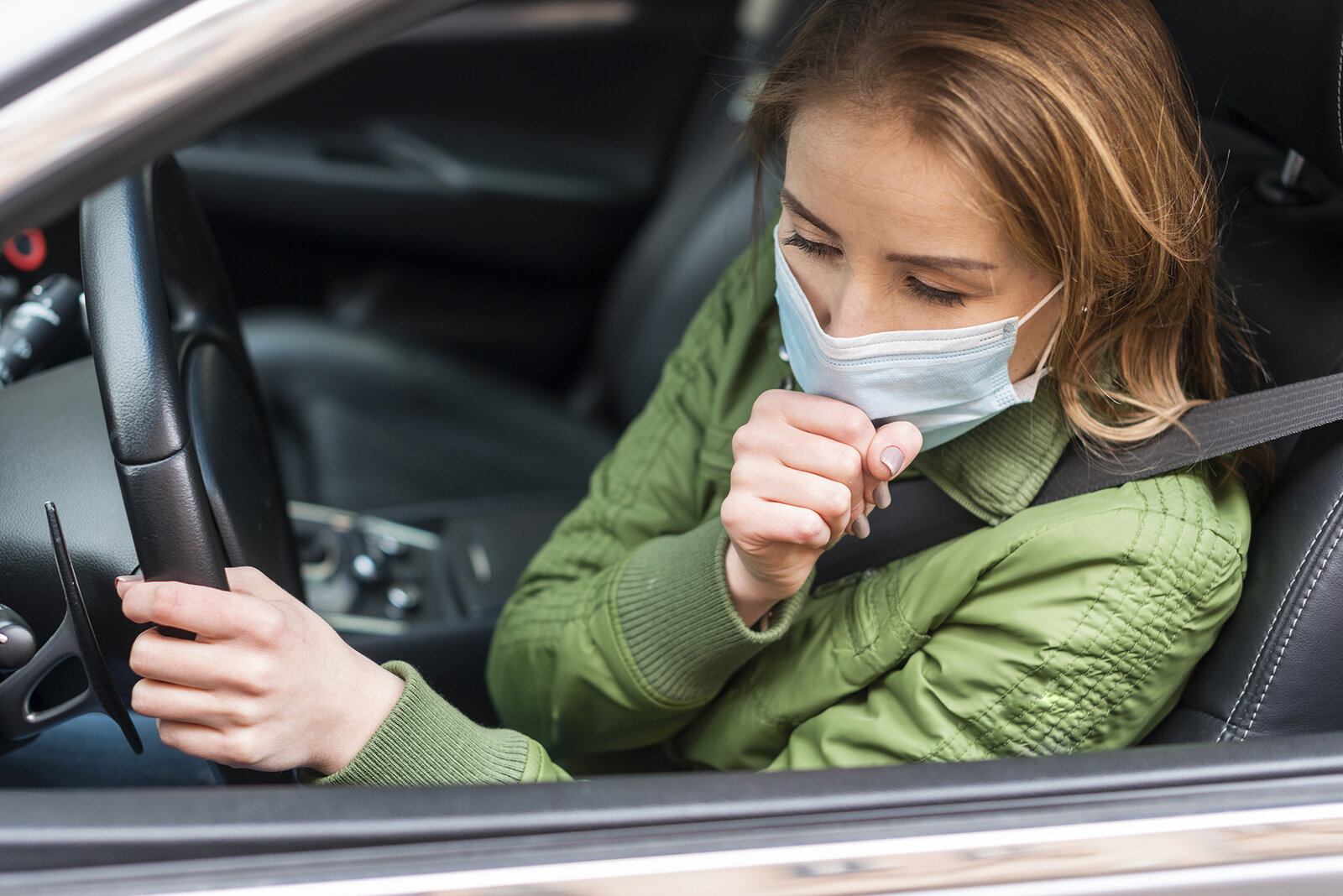 Frau mit Schutzmaske im Auto