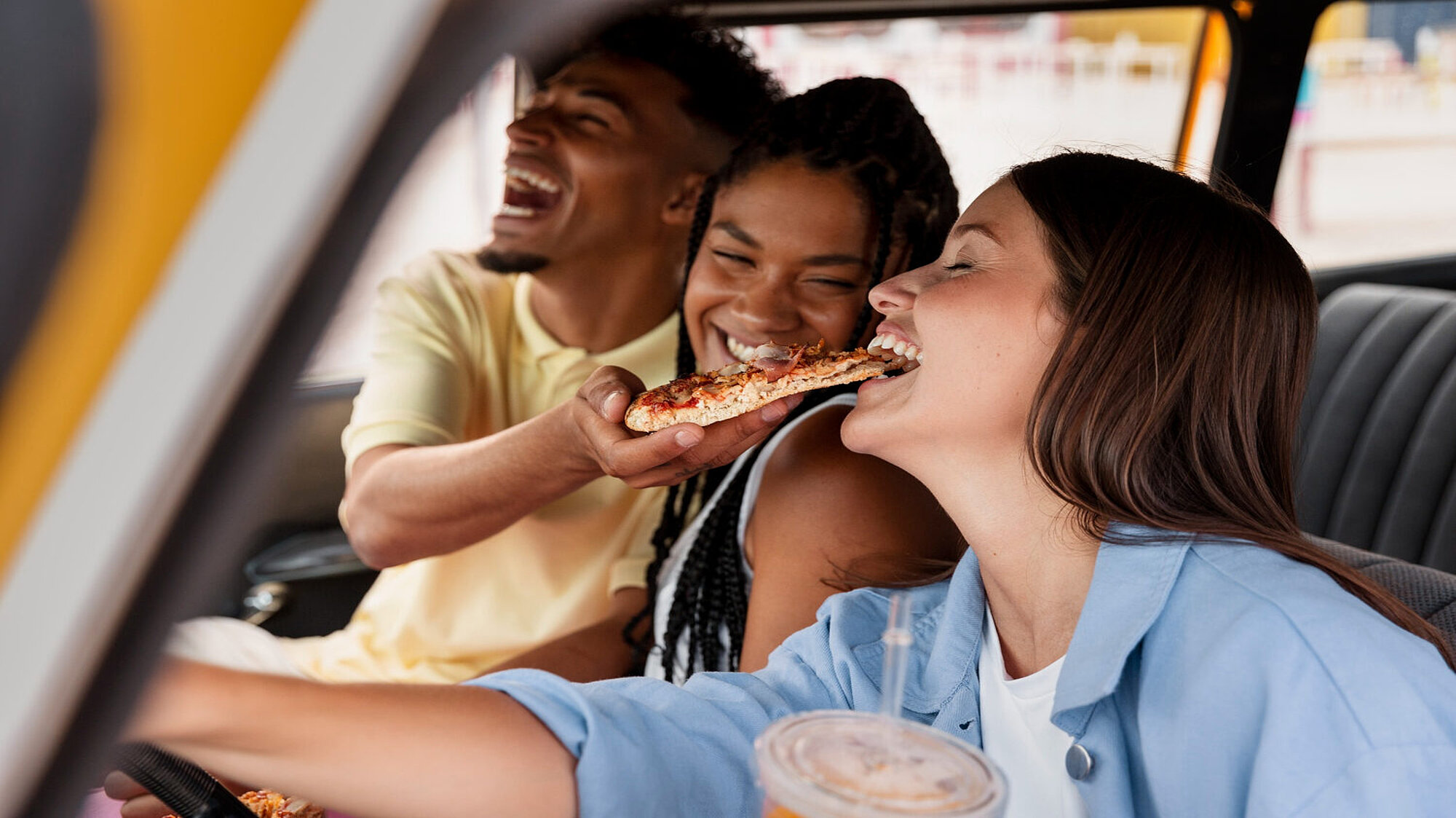Freunde essen eine Pizza im Auto
