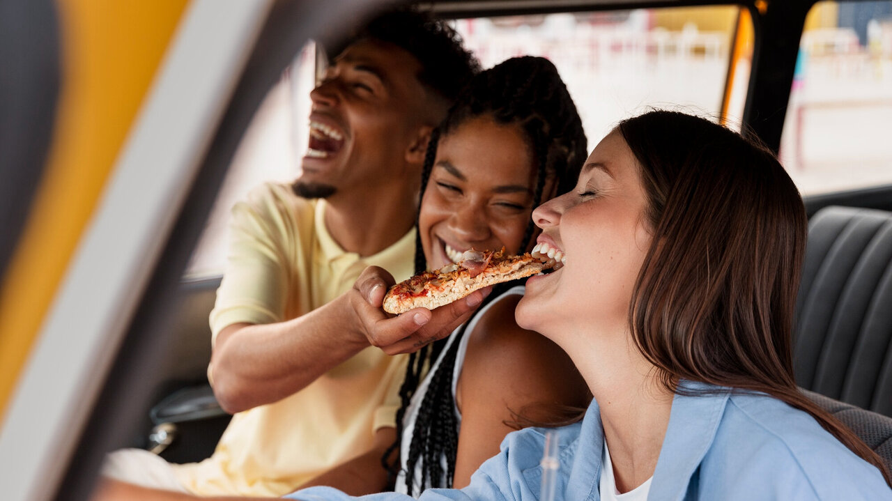 Freunde essen eine Pizza im Auto