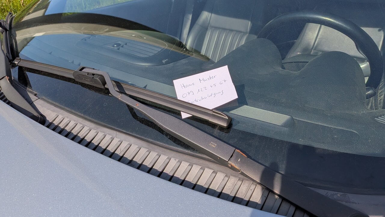 Notiz mit Kontaktdaten unter dem Scheibenwischer