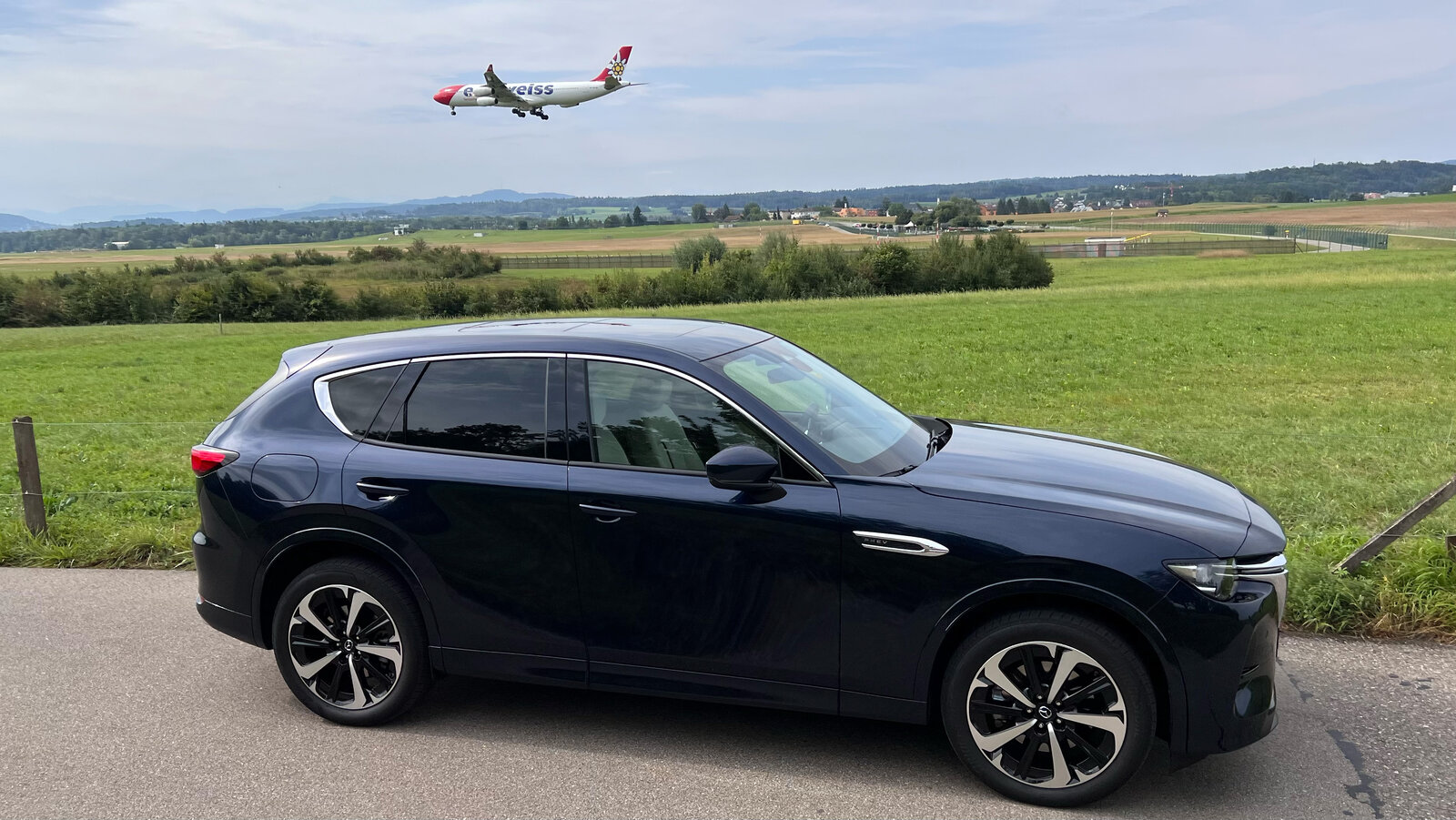 Seitenansicht des Mazda CX-60 mit Flugzeug im Hintergrund