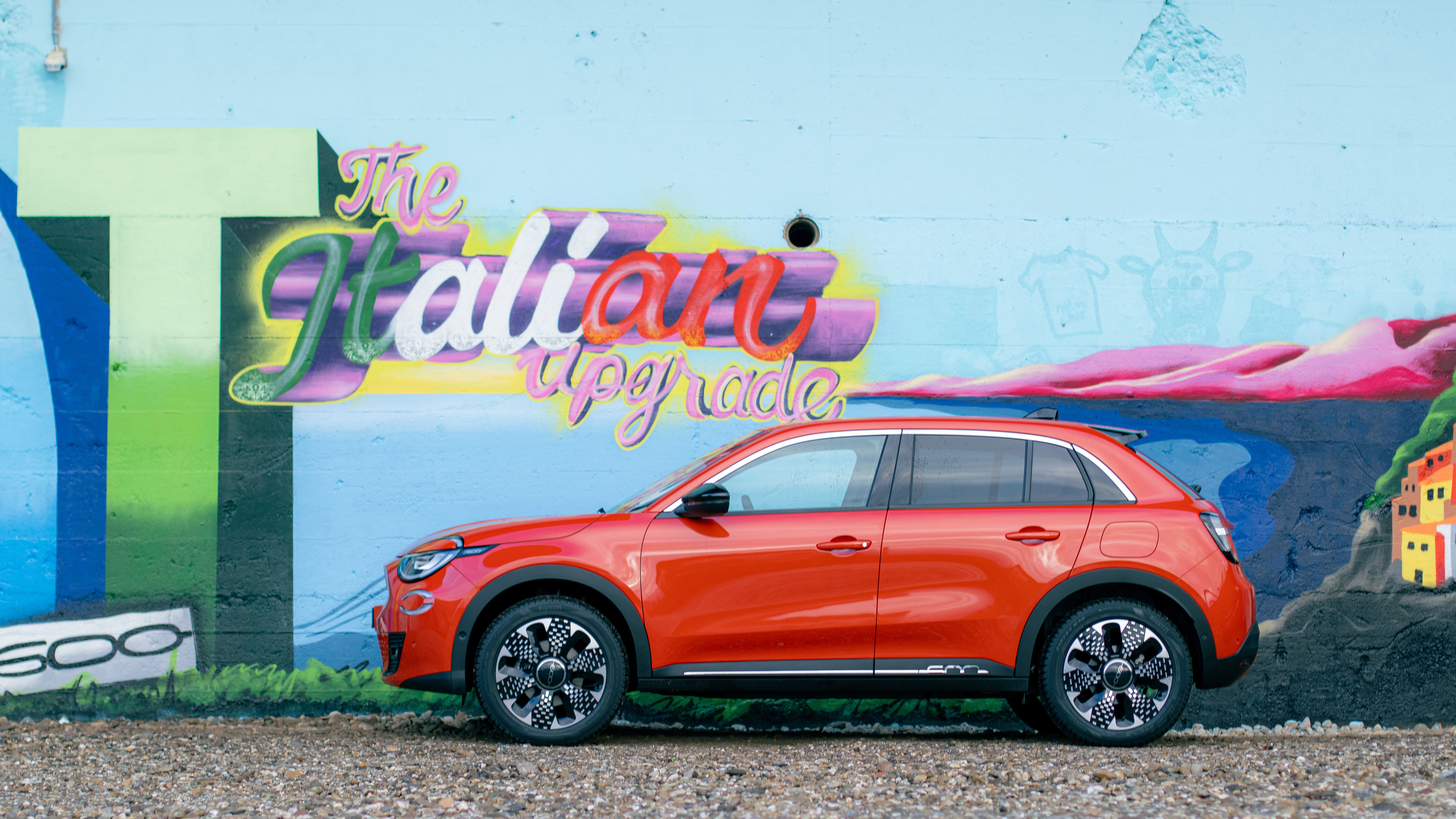 Fiat 600e seitlich vor einem Graffiti