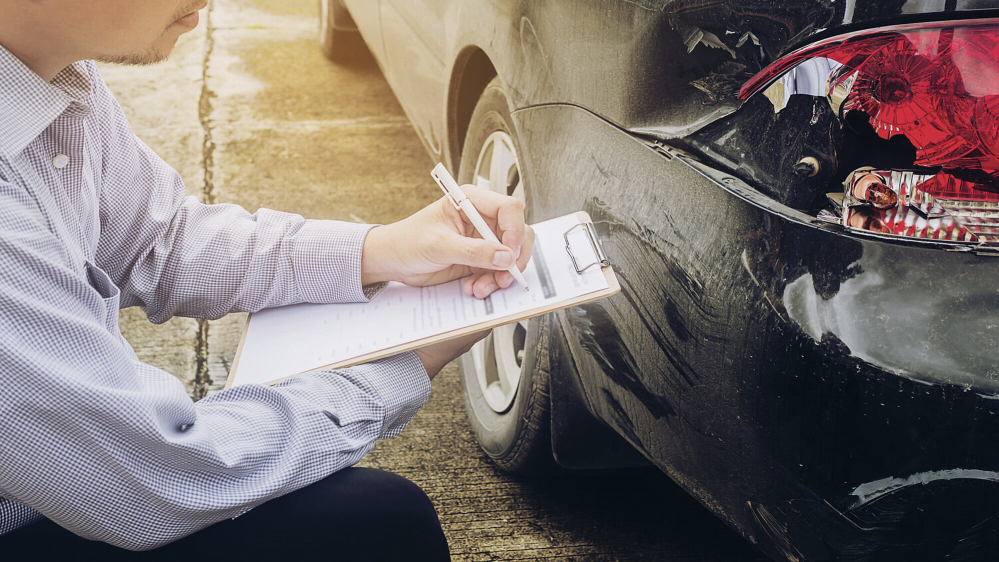 Ein Person notiert Schäden an einem Auto