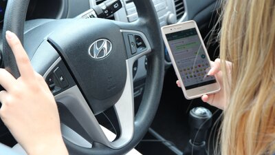 Frau mit dem Handy am Steuer