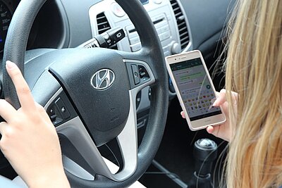 Frau mit dem Handy am Steuer