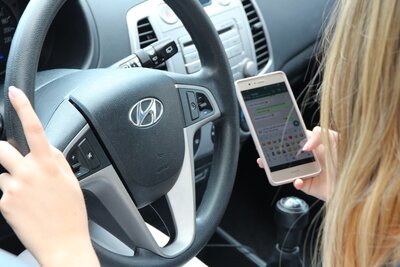 Frau mit dem Handy am Steuer