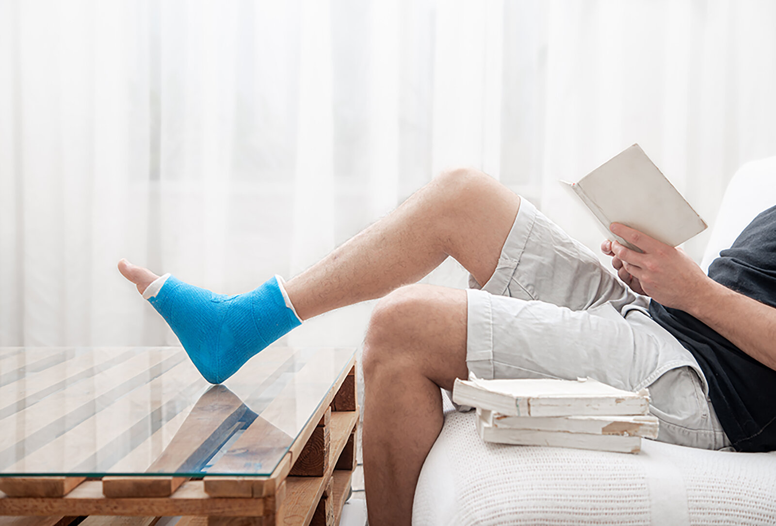 Mann mit gebrochenen Bein liest Buch
