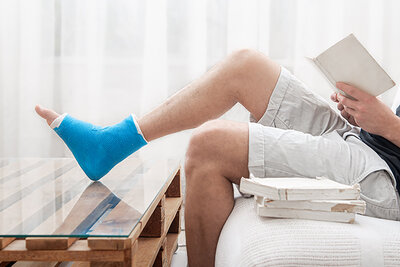 Mann mit gebrochenen Bein liest Buch
