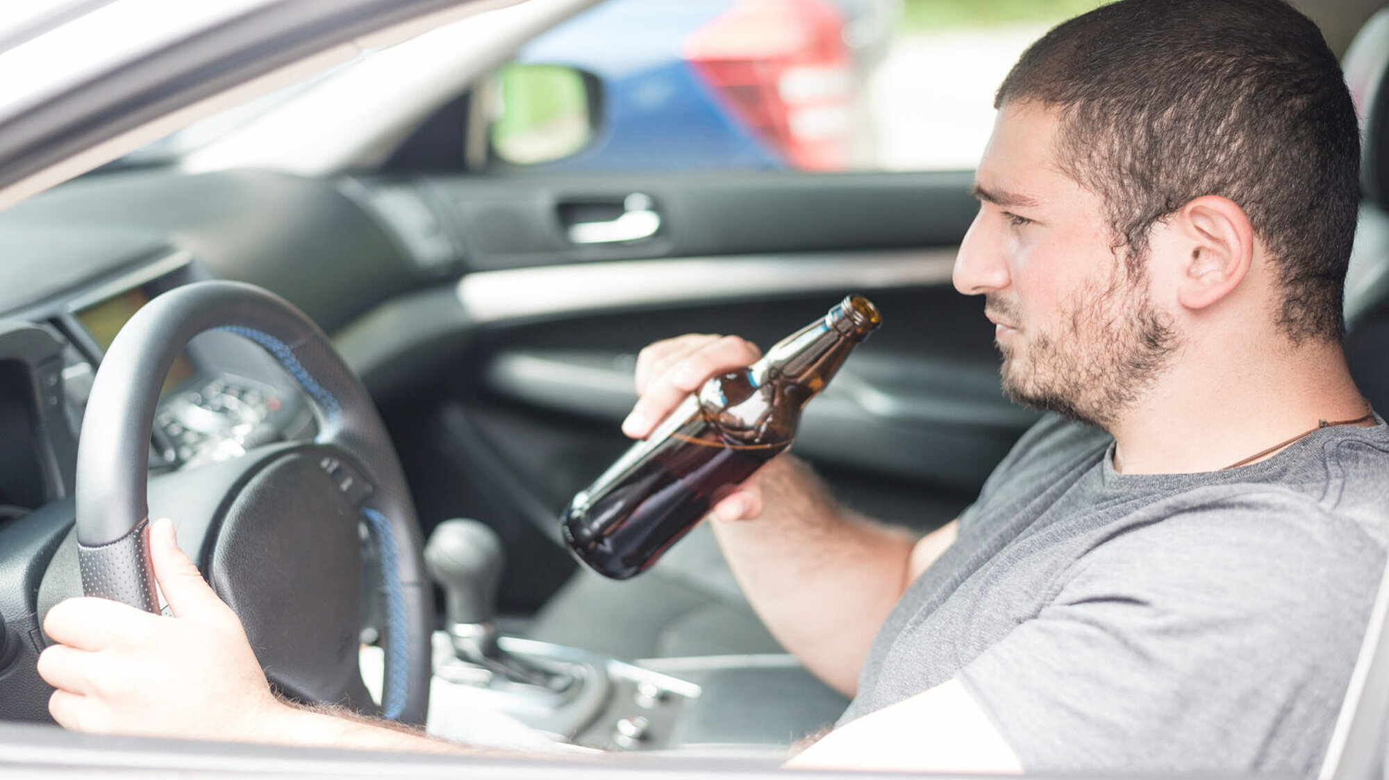 Ein Mann trinkt ein Bier während der Fahrt