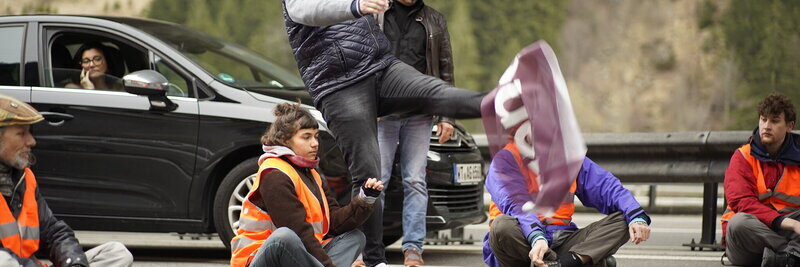 Unbeteiligter Kick in Demonstrationsplakat von Klimaklebern