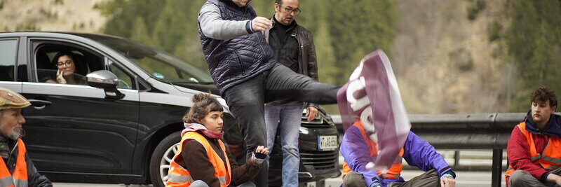 Unbeteiligter Kick in Demonstrationsplakat von Klimaklebern