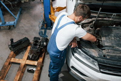 Ein Mechaniker arbeitet im Motorraum eines Autos