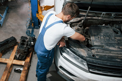 Ein Mechaniker arbeitet im Motorraum eines Autos