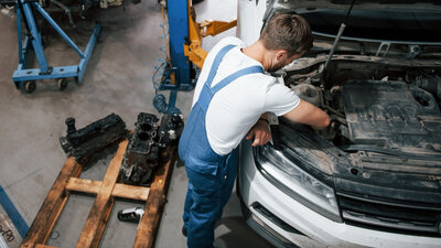 Ein Mechaniker arbeitet im Motorraum eines Autos