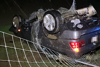 Nach der Kollision mit dem Wildschutzzaun blieb der BMW auf dem Dach in der Wiese liegen. Bild: Kantonspolizei Solothurn