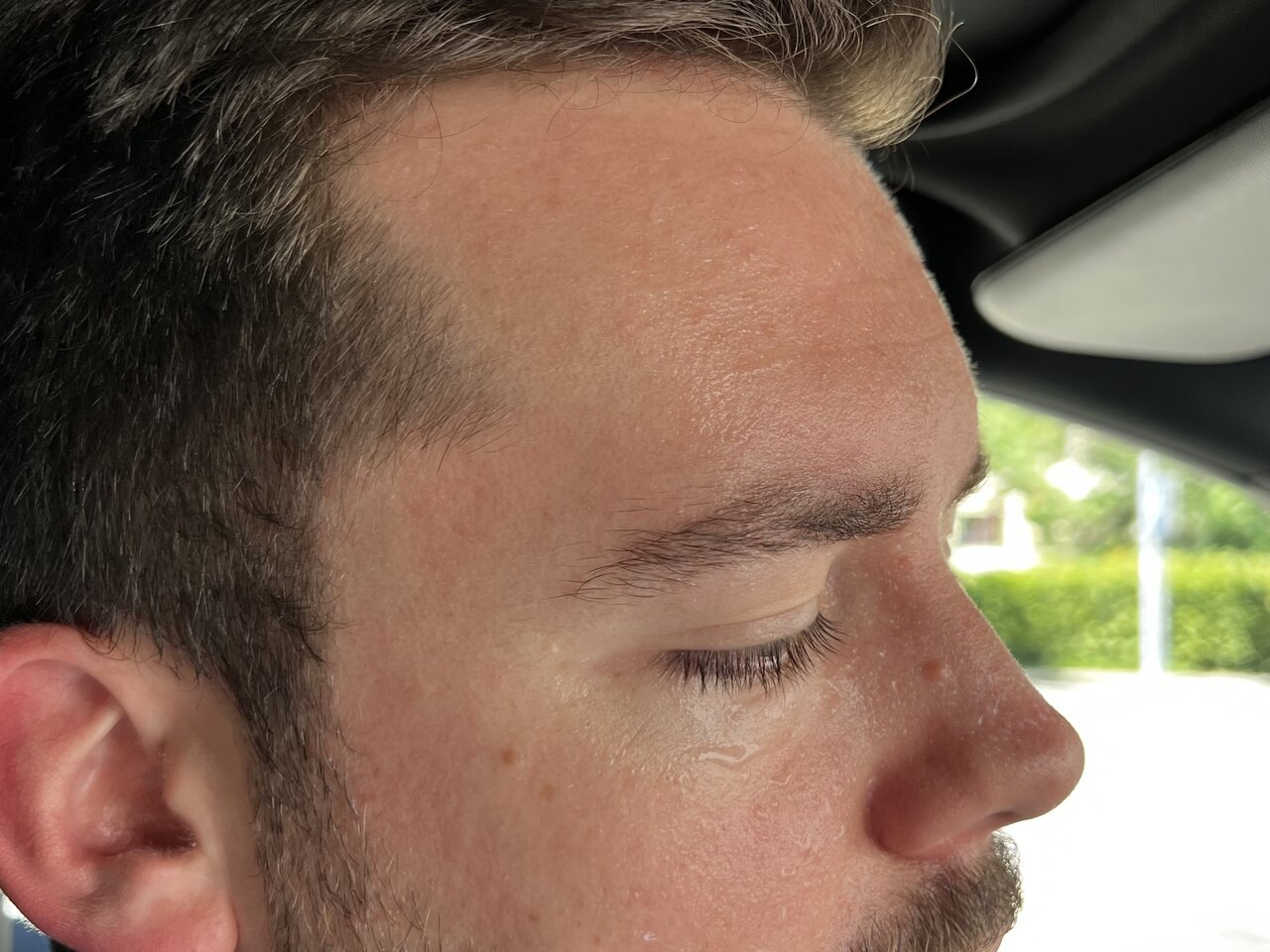 Redaktor Linus Barta mit Thermometer und Telefon in der Hand im Auto