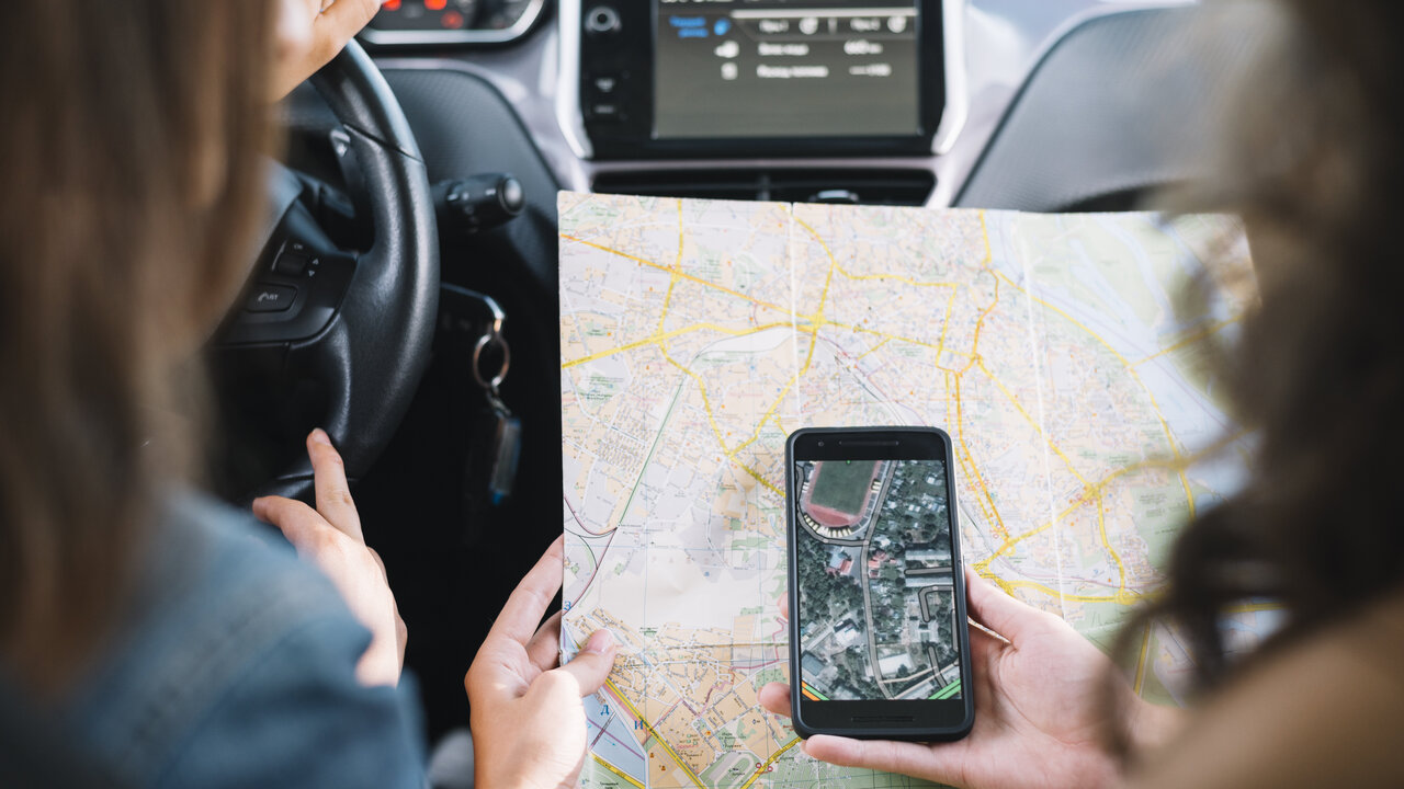Zwei Frauen konsultieren im Auto das Handy und eine Strassenkarte