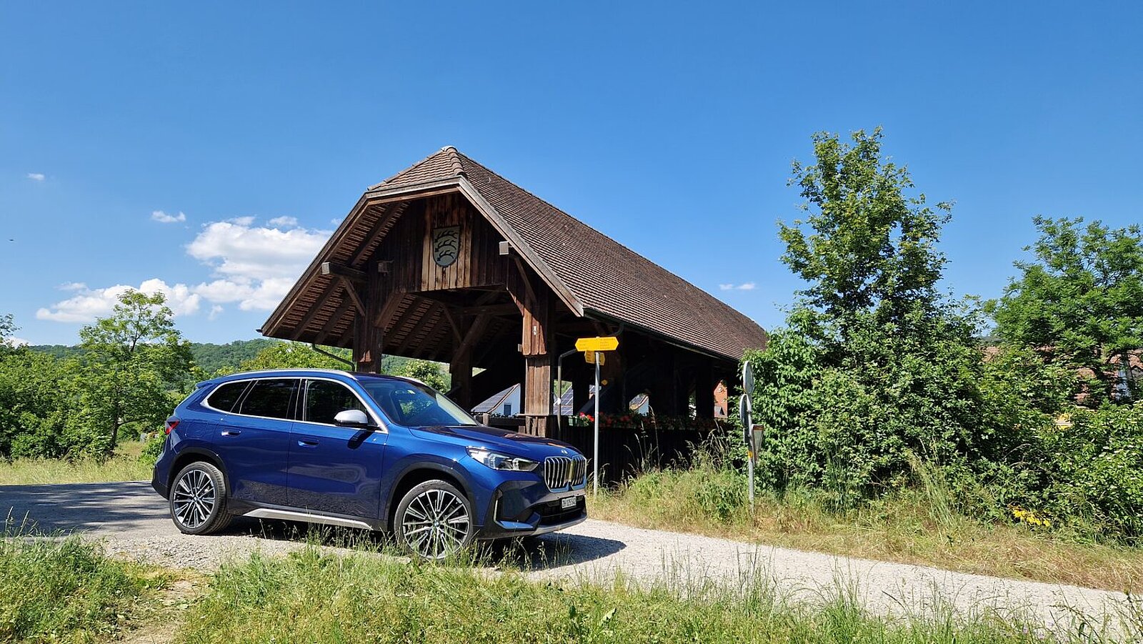 Der BMW X1 von vorne vor einer Schweizer Holzbrücke