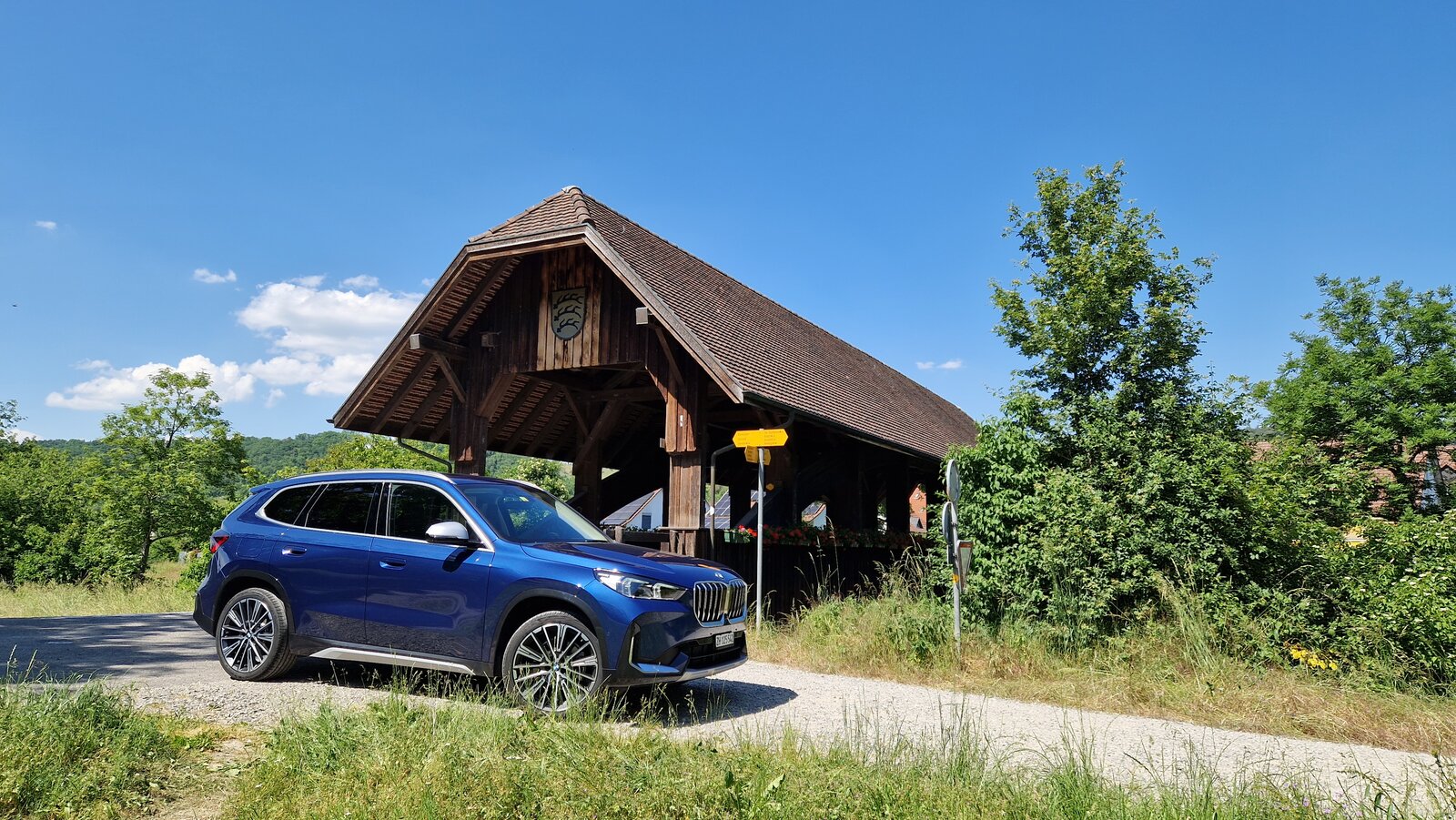 Der BMW X1 von vorne vor einer Schweizer Holzbrücke