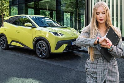 Frau wartet, BYD Dolphin Surf im Hintergrund