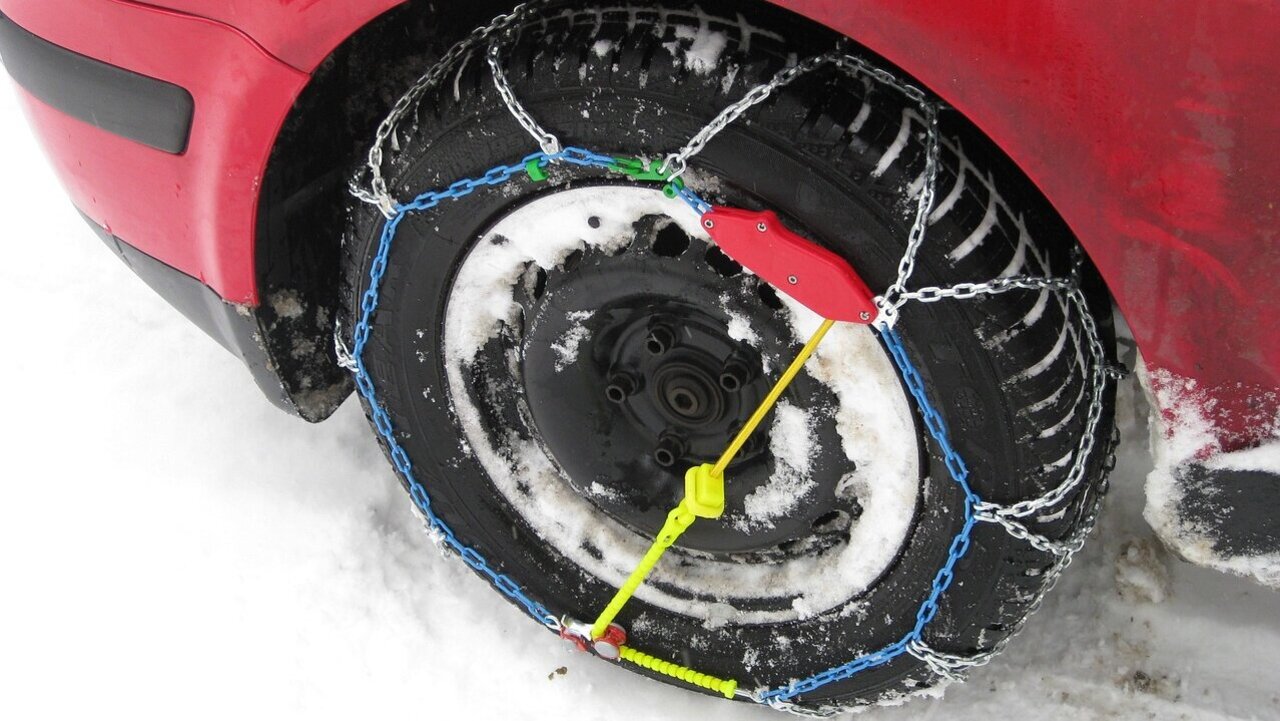 Rotes Auto mit Schneeketten.