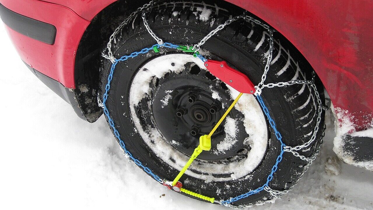 Rotes Auto mit Schneeketten.