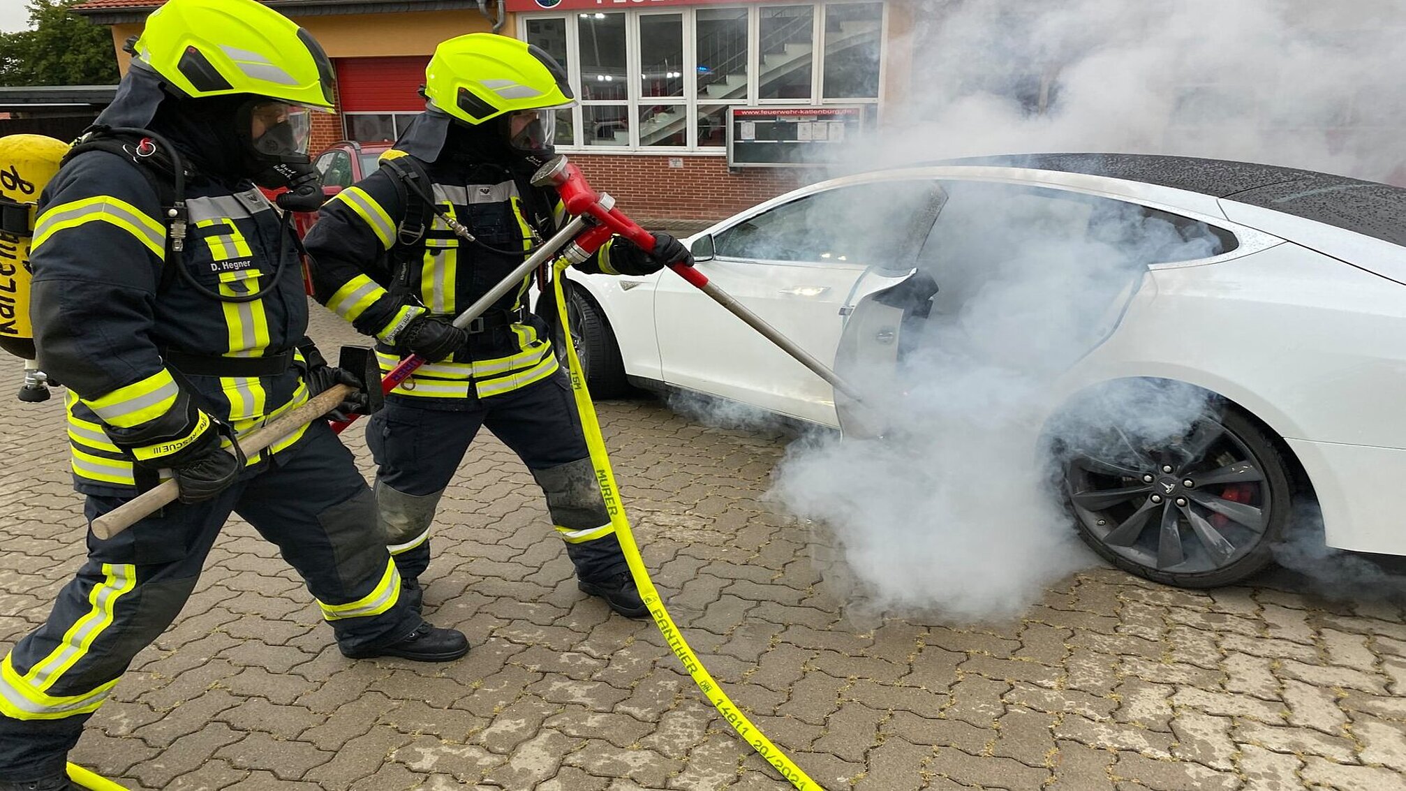Feuer bekämpft ein Feuer in einem Tesla mit einer Löschlanze