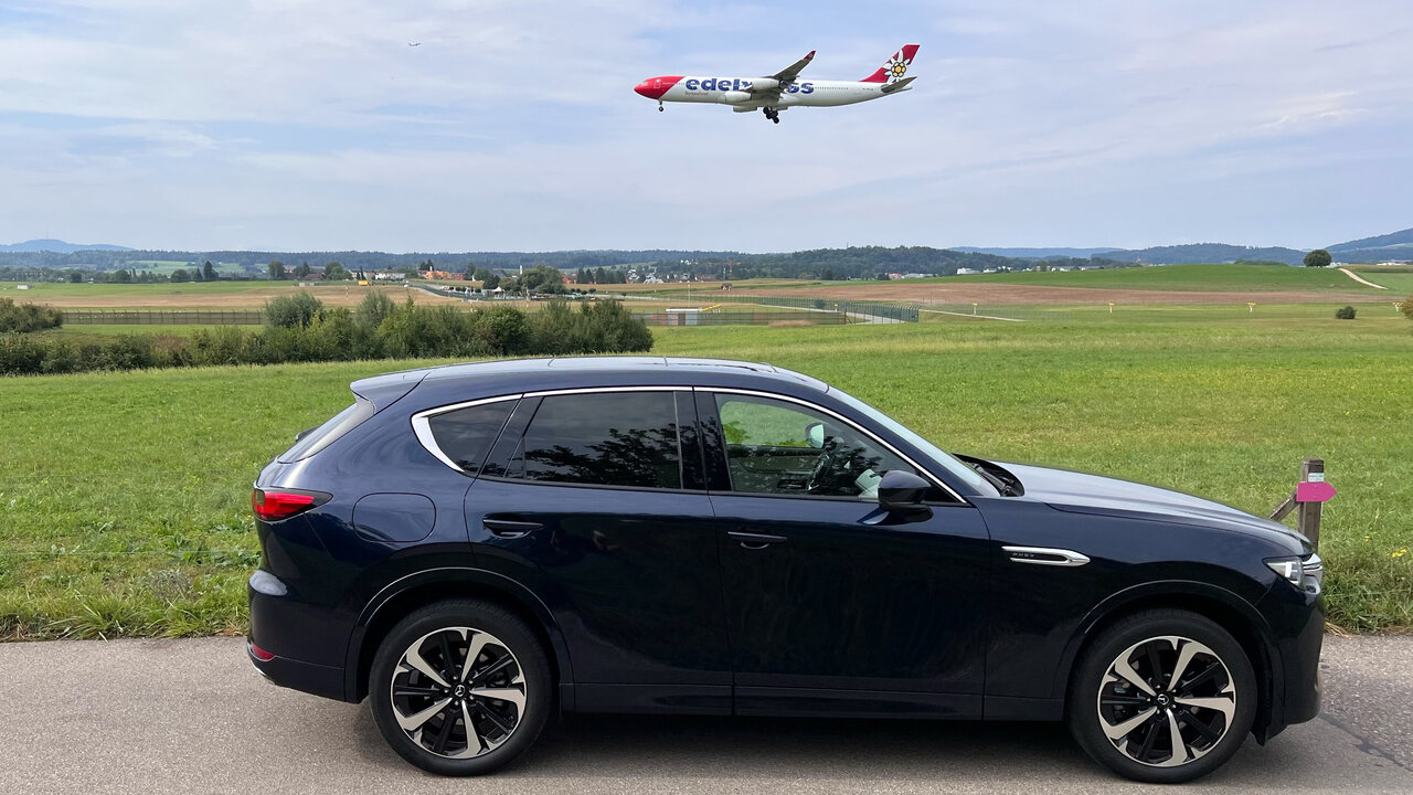 Seitenansicht des Mazda CX-60 mit Flugzeug im Hintergrund
