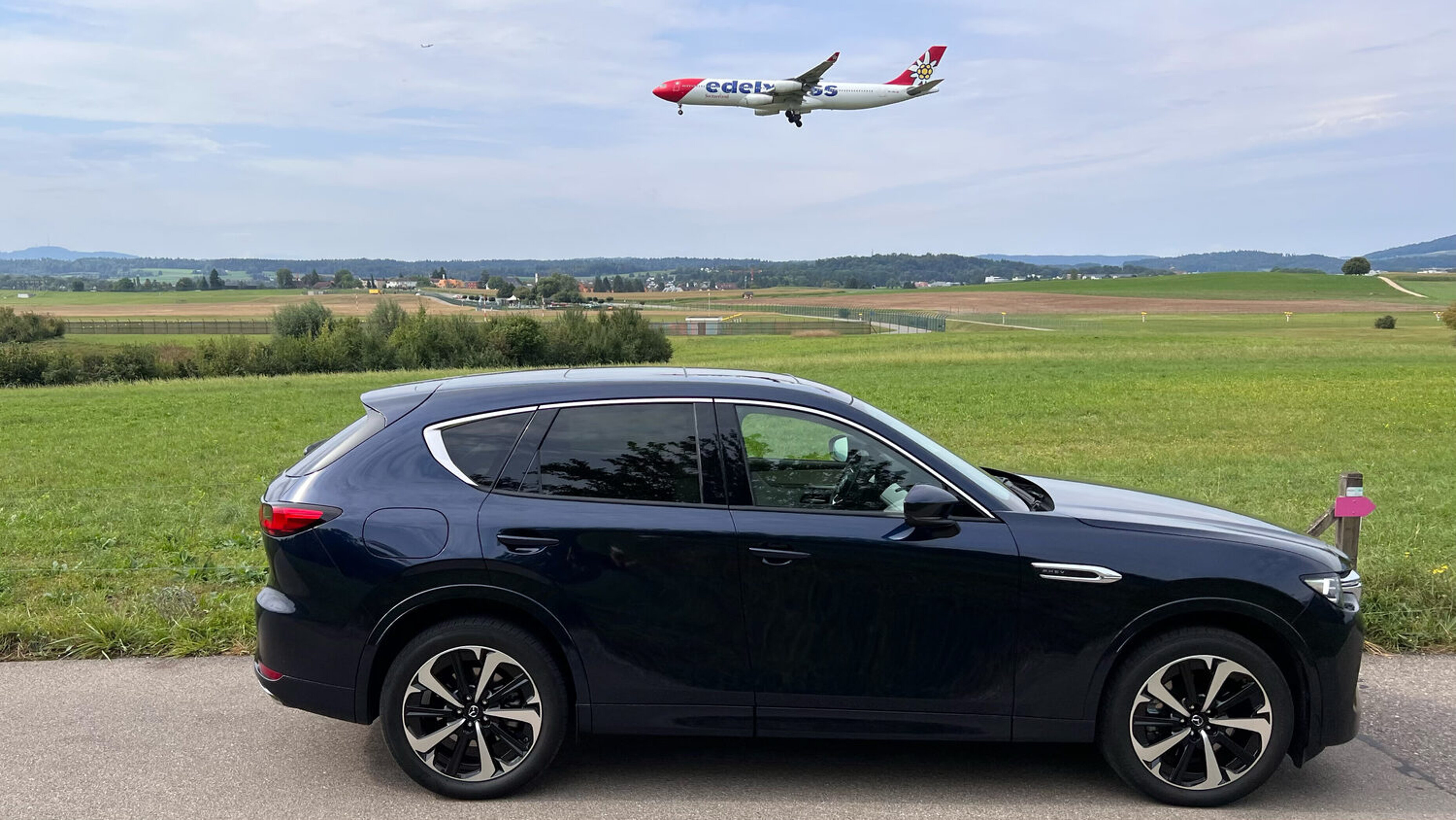Seitenansicht des Mazda CX-60 mit Flugzeug im Hintergrund