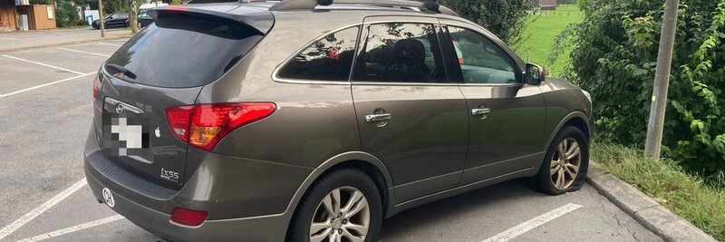 Auto auf Parkplatz mit plattem Reifen